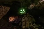 A carved Halloween pumpkin face on a rock inside a dark cave