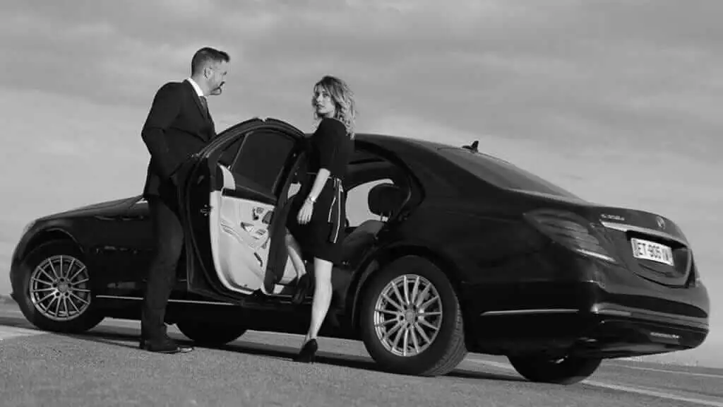 A man and woman standing next to a mercedes - benz s-class.