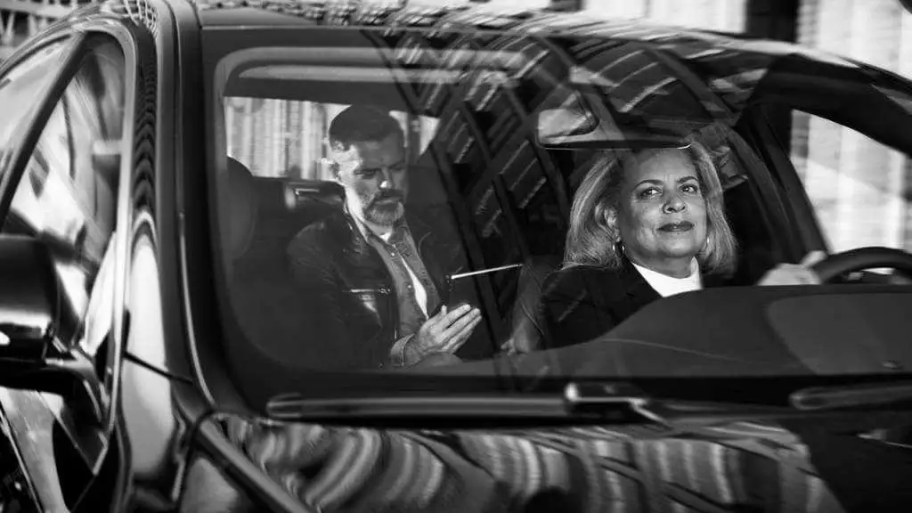 A black and white photo of a couple in a car, showcasing the charm of a chauffeur service.