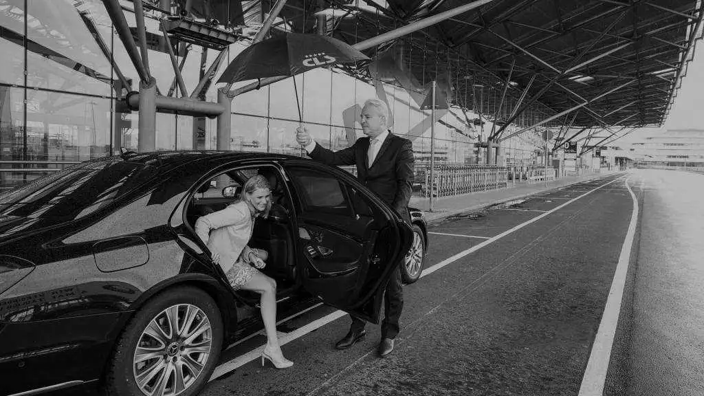 A man and woman standing next to a car at an airport.