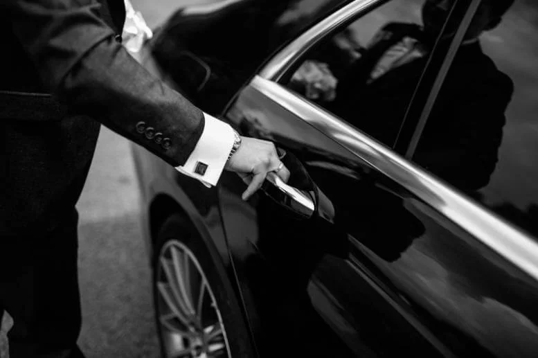 A man in a suit is opening the door of the best car service.