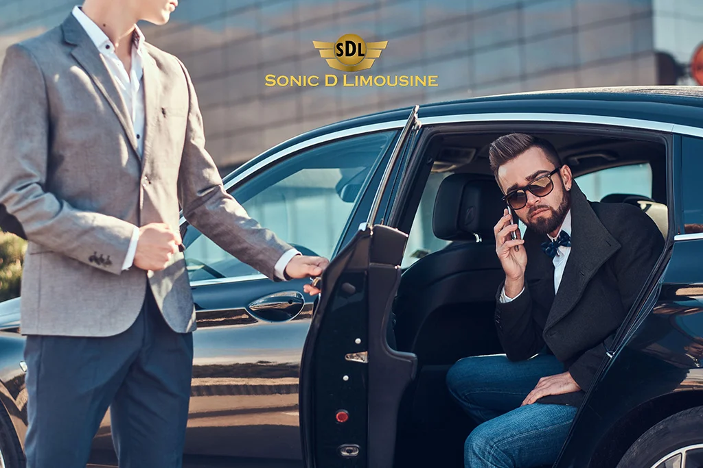 A man is talking on the phone while sitting in Sonic D Limousine car.
