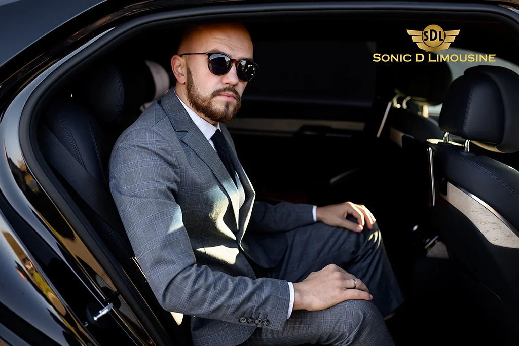 Sonic D Limousine A man in a suit sitting in the back seat of a car.